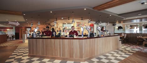 A reception area with a checkered floor, wooden reception desk, and multiple bar counters.