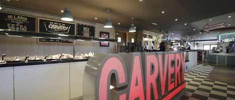 Restaurante Carvery con un letrero grande, una barra de comida y un suelo a cuadros.