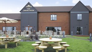 A building named 'The Spring River' with a brick facade, multiple windows, and outdoor seating with tables and chairs. - Spring River Ebbsfleet by Marston's Inns (Gravesend)