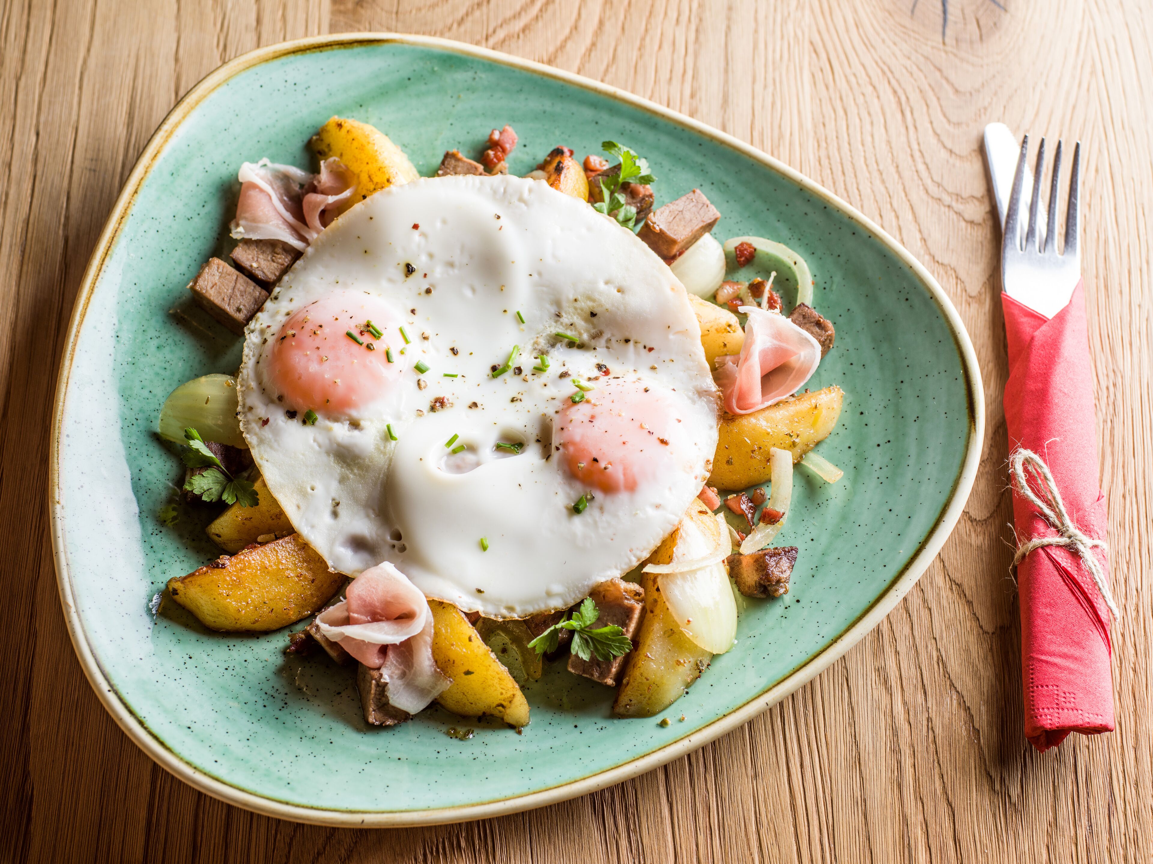 A plate of food with eggs, potatoes, and bacon on a green plate.