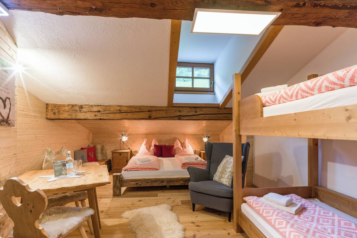 Una habitación acogedora de estilo cabaña con una cama litera, un escritorio con silla, una mesita pequeña y una alfombra mullida.