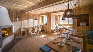 Interior rústic de fusta amb una llar de foc, taules i caires de fusta, i un rètol amb el nom 'BERGKOF KAISERTAL'.