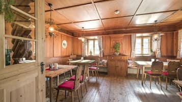 Interior de madera con comedor, techo de madera y ventana con cortinas.