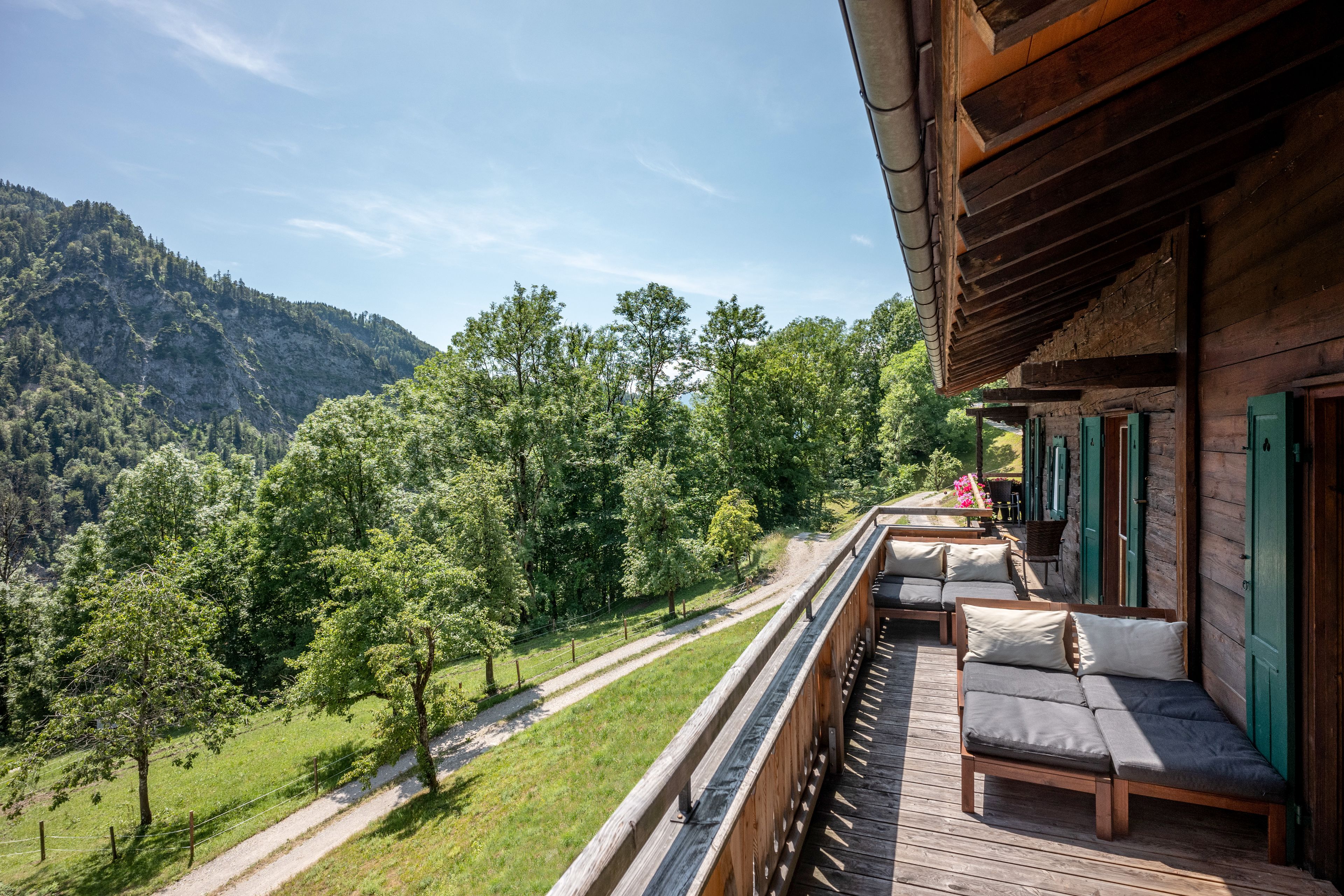 Un terrazzo in legno con posti a sedere all'aperto e vista su un paesaggio montano.