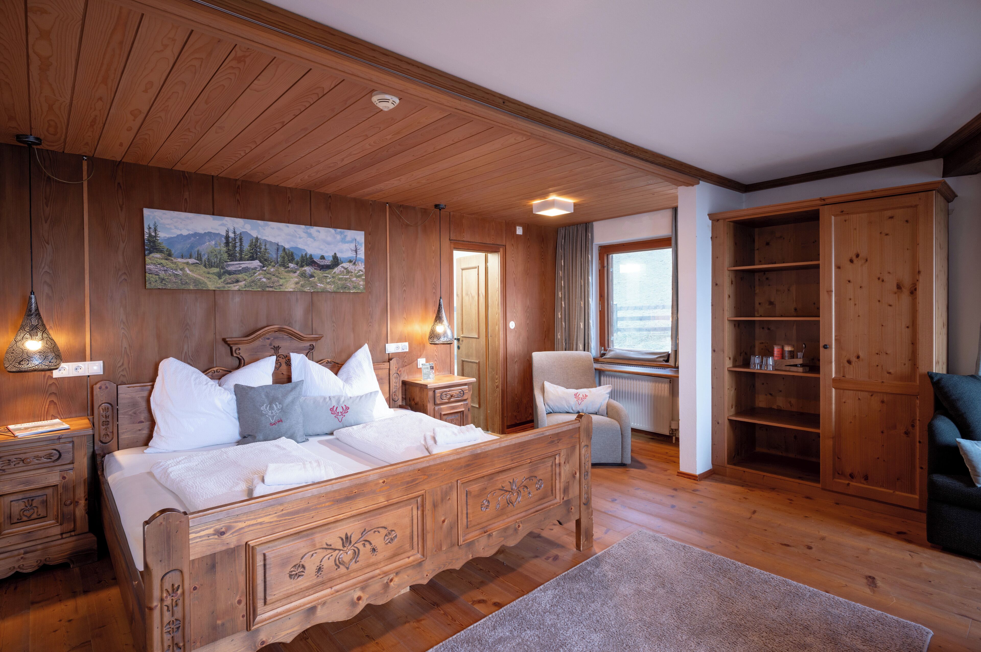 A wooden bedroom with a bed, nightstands, a chair, a wardrobe, and a painting on the wall.