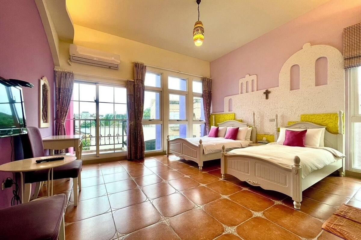 A bedroom with two beds, a TV, and a balcony.