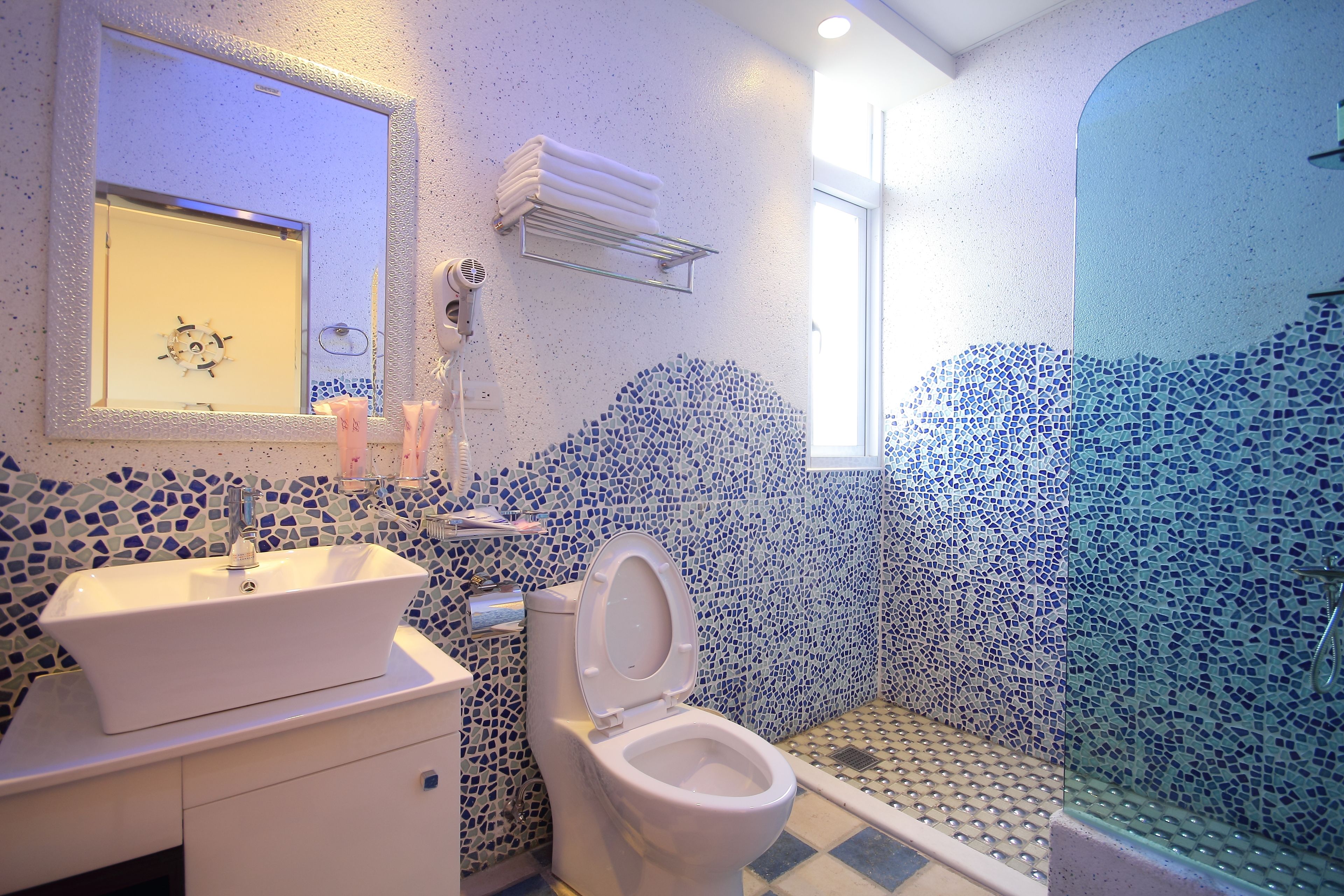 Un baño con pared de mosaicos, un lavamanos blanco y un inodoro.