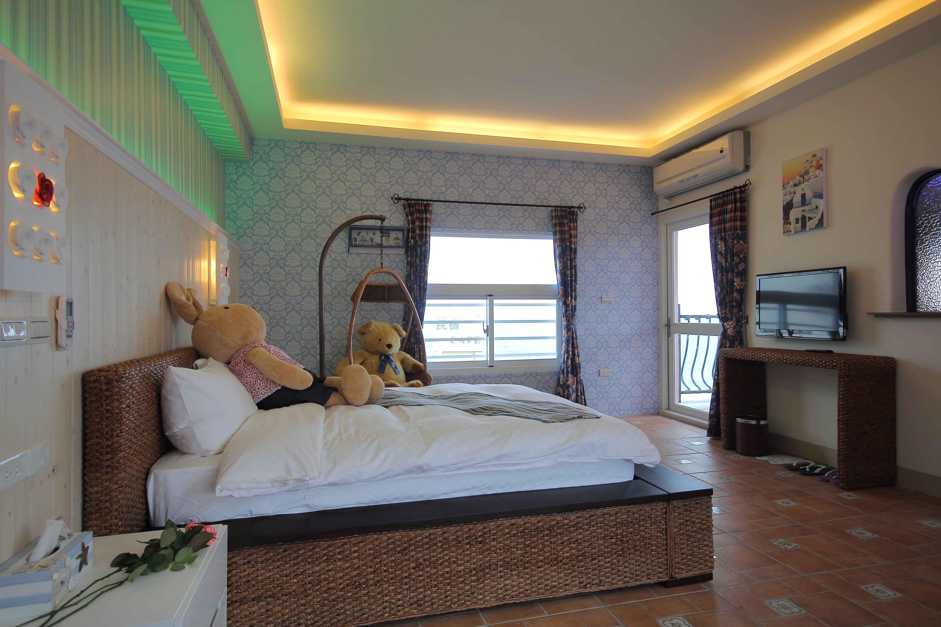 Un dormitorio con una cama grande, televisión y una ventana con cortinas.