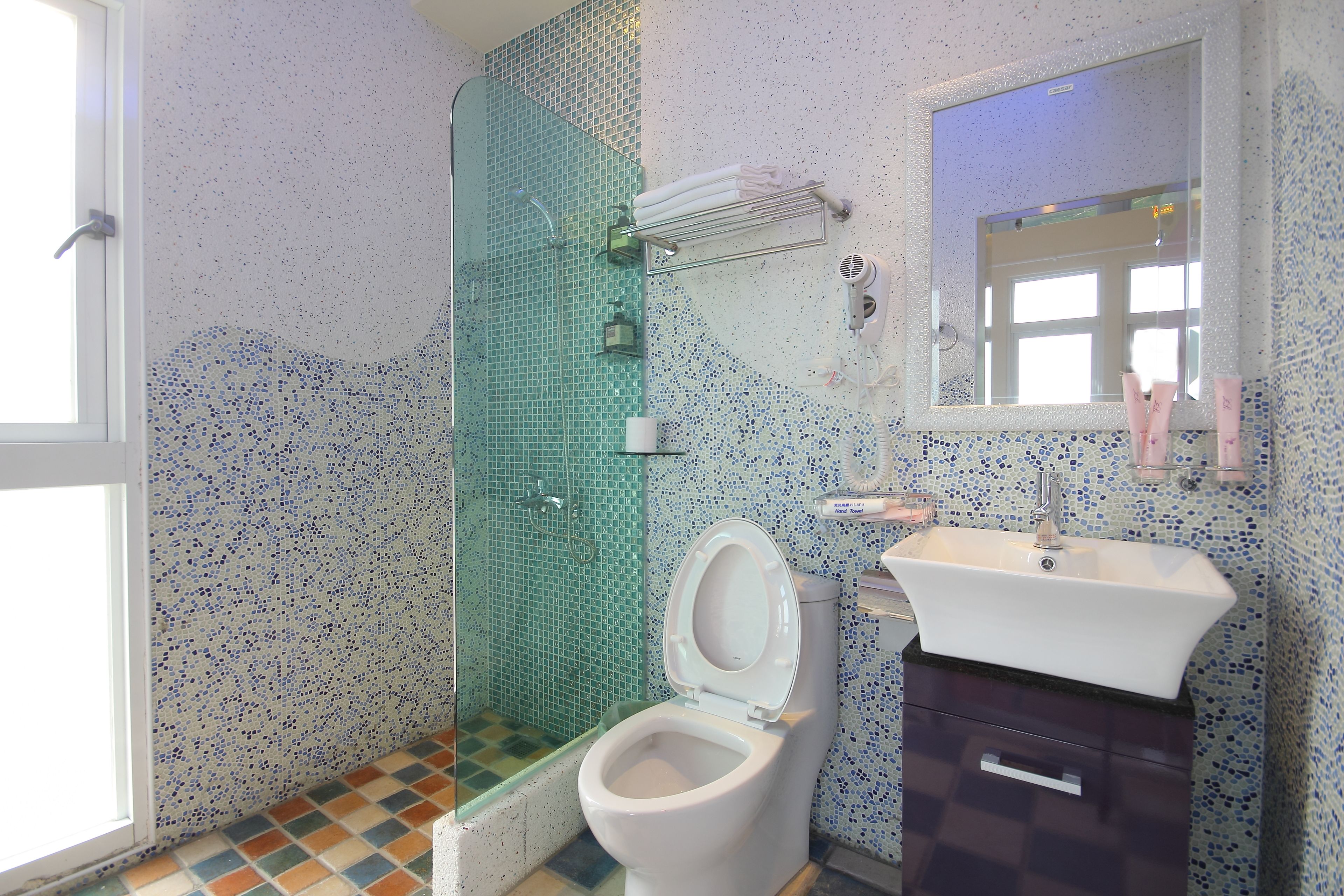 Une salle de bain équipée d’une douche, de toilettes, d’un lavabo et d’un miroir.