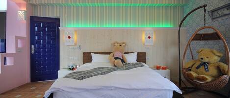 Une chambre à coucher avec un lit, un ours en peluche sur le lit, une chaise suspendue et une porte bleue.