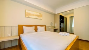 A hotel room with a large bed, a bedside table, a mirror, and a wardrobe. - Cozy 2 Bedrooms Sudirman Tower Apartment by Travelio (Jakarta)