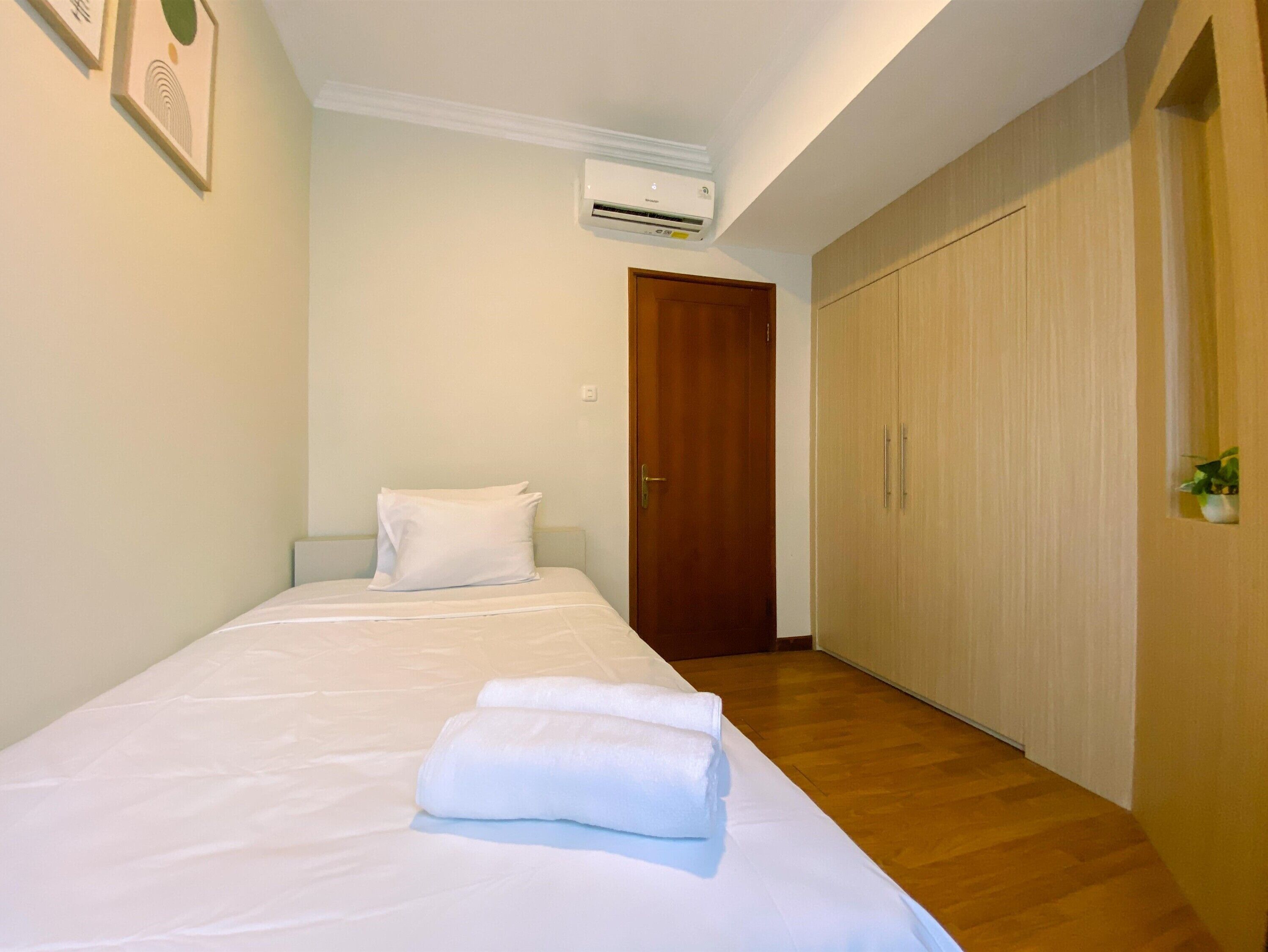 A bedroom with a bed, a wooden wardrobe, and an air conditioning unit on the wall.
