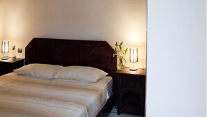 Un dormitorio con una cama grande, dos lámparas de noche, una lámpara de pared y un tapiz de pared tejido.