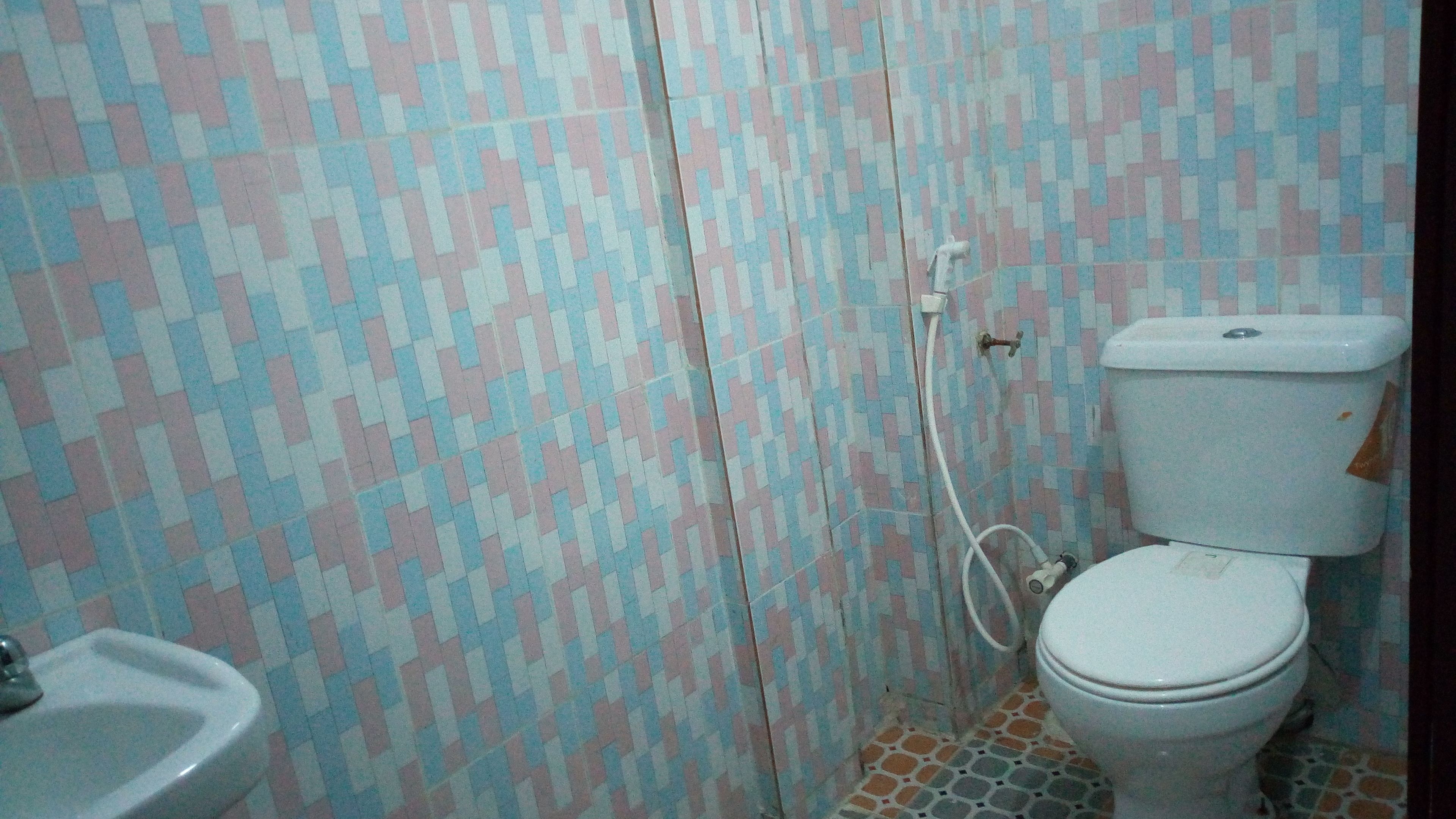 A bathroom with a patterned tile wall, a toilet, and a sink.