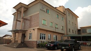 A multi-story hotel with a stone facade, multiple windows, and a parking area with a black pickup truck. - D'Czars Hotel & Suites (Lagos)