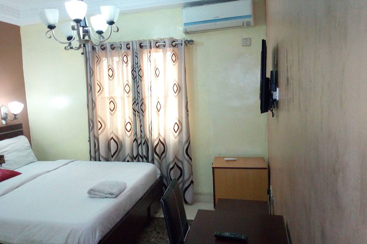 A hotel room with a bed, a television, a desk, and a chair.