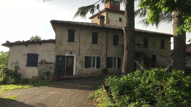 Un edificio de piedra rústico con un gran árbol en primer plano.