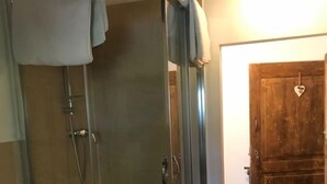 Ducha envuelta en vidrio, con cabezal de ducha y un rociador de mano.
