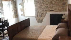 Un dormitorio con pared de piedra, cama de madera y radiador.