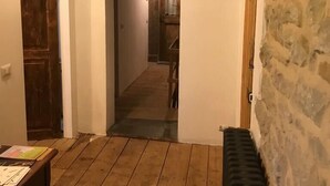 Un pasillo con pared de piedra, suelo de madera y un radiador.