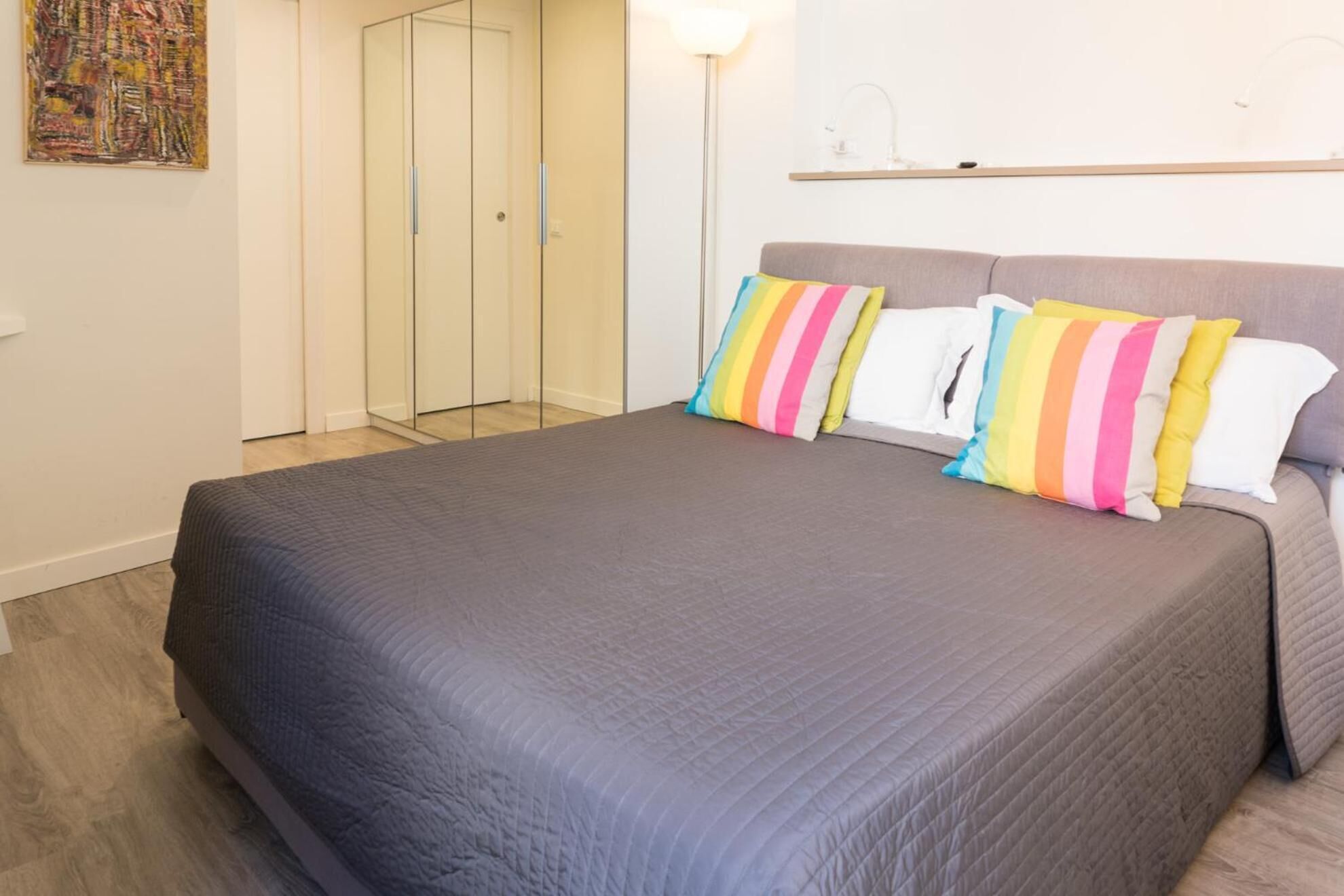 Ein Schlafzimmer mit einem Bett, einem Kleiderschrank und einer Stehlampe.