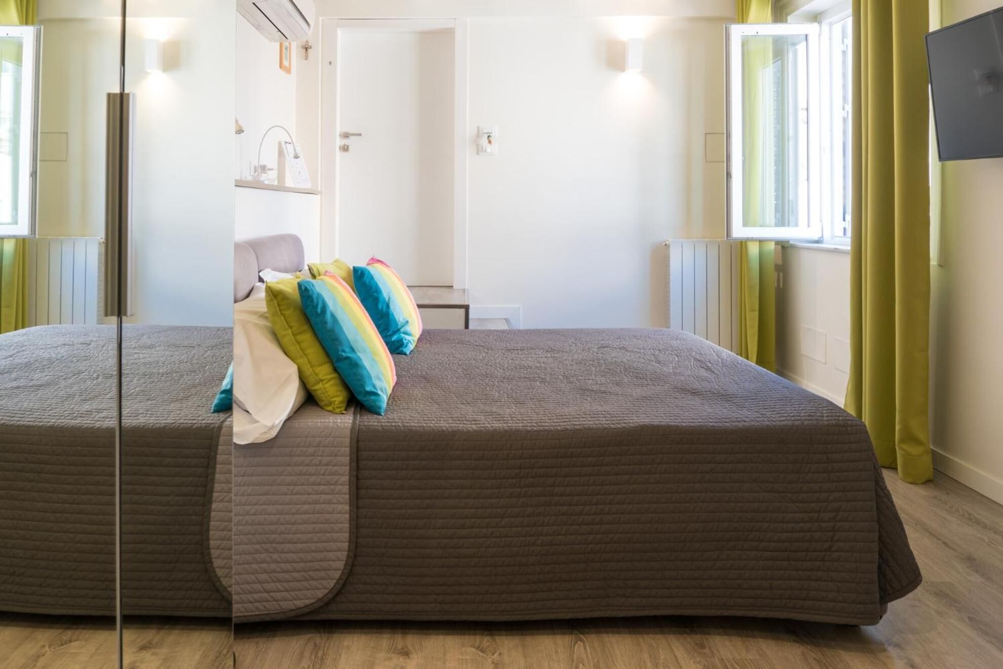 A room with a large bed, a bedside table, and a window with curtains.