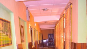 Un pasillo de hotel con suelo de baldosas, paneles de madera en las paredes y obras de arte enmarcadas.