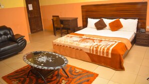 Una habitación de hotel con cama, escritorio, silla, sofá de cuero y una pequeña mesa.