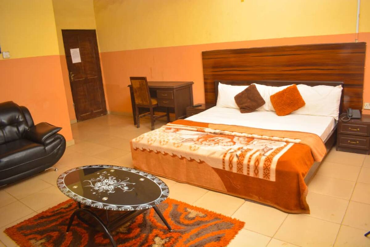 Une chambre d’hôtel comprenant un lit, un bureau, une chaise, un canapé en cuir et une petite table.