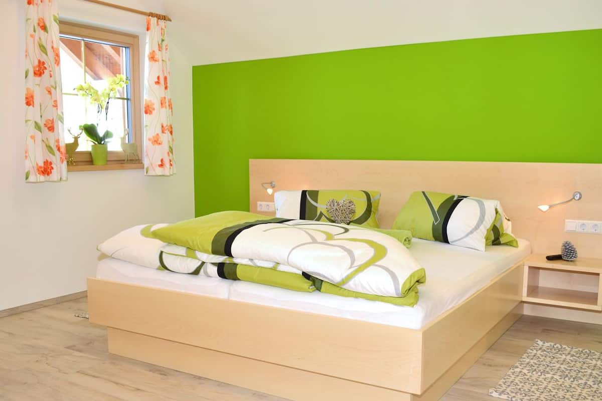 A bedroom with a bed, a nightstand, a lamp, and a window with curtains.