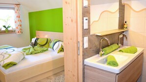 Un dormitorio con cama, cabecera verde y baño con lavabo y espejo.