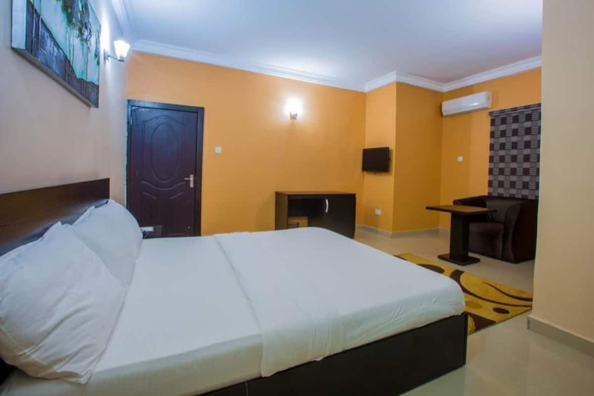 A hotel room with a bed, a desk, a chair, and a television.