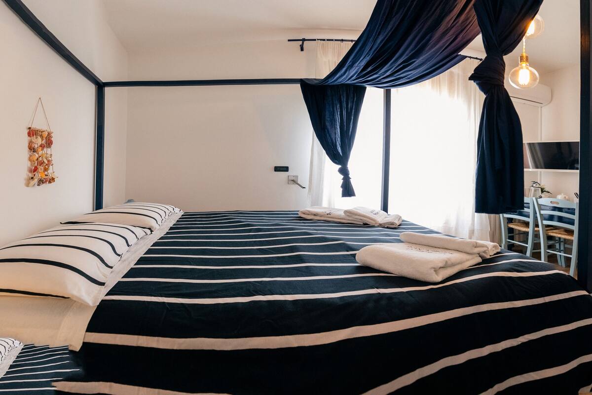 Une chambre d’hôtel avec un grand lit, un bureau et une salle de bain visible à travers une porte ouverte.