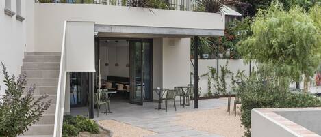 A modern two-story house with a patio area featuring outdoor furniture and a piano.