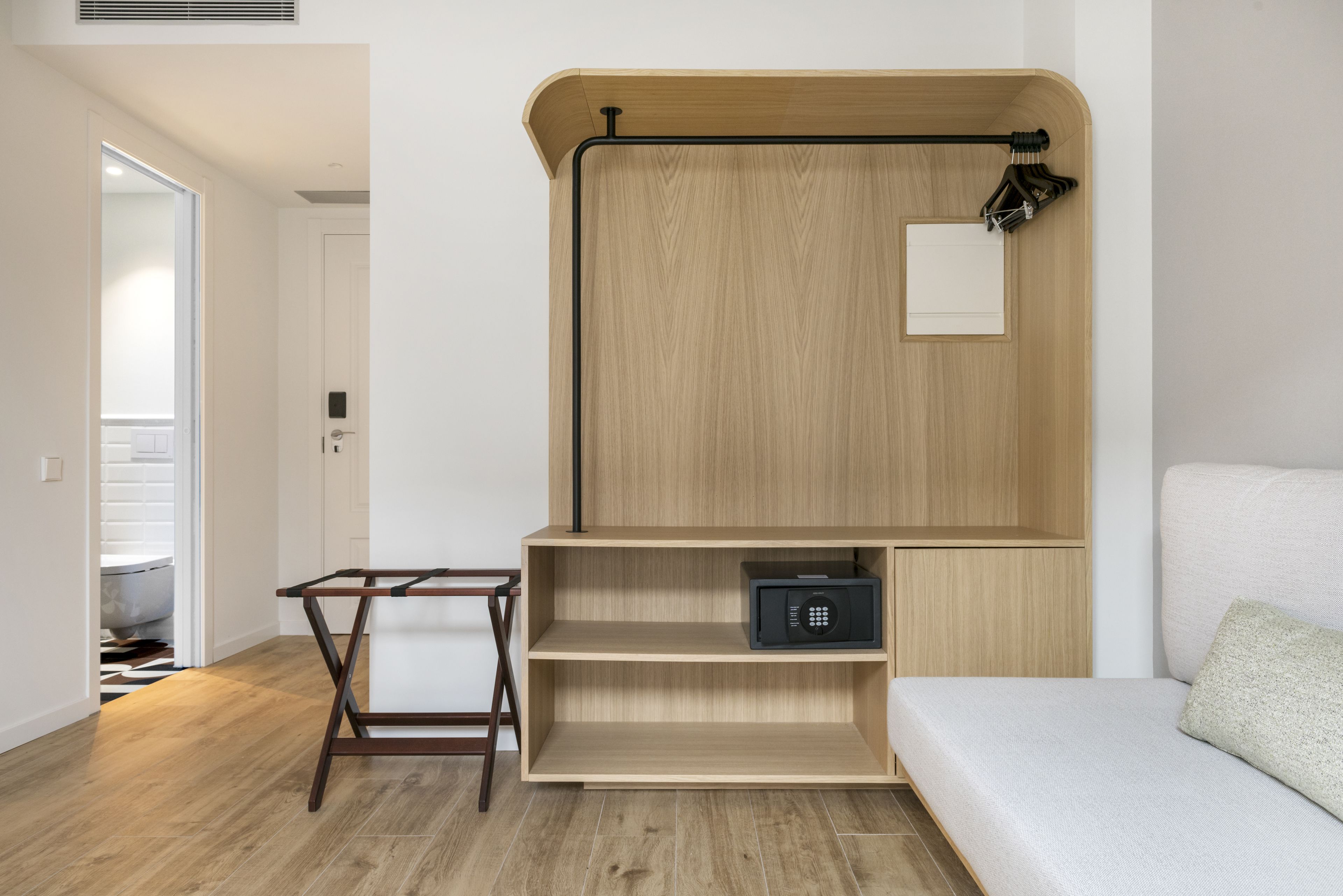 A modern room with a wooden cabinet, a black safe, and a white sofa.