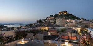 Terraza en la azotea con mobiliario exterior y vistas a un cerro histórico con un castillo.