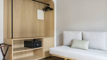 A modern room with a wooden cabinet, a black electronic device, and a white sofa with a cushion.