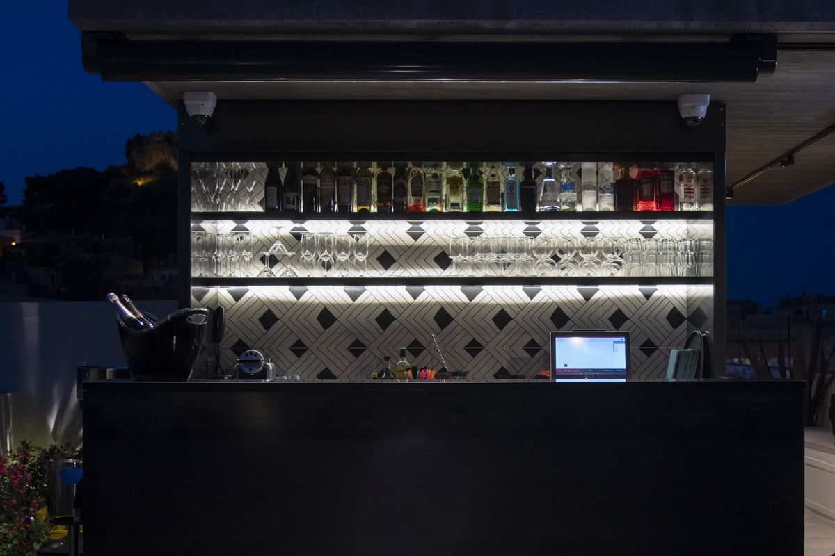 A bar area with a computer monitor, shelves of bottles, and glasses.