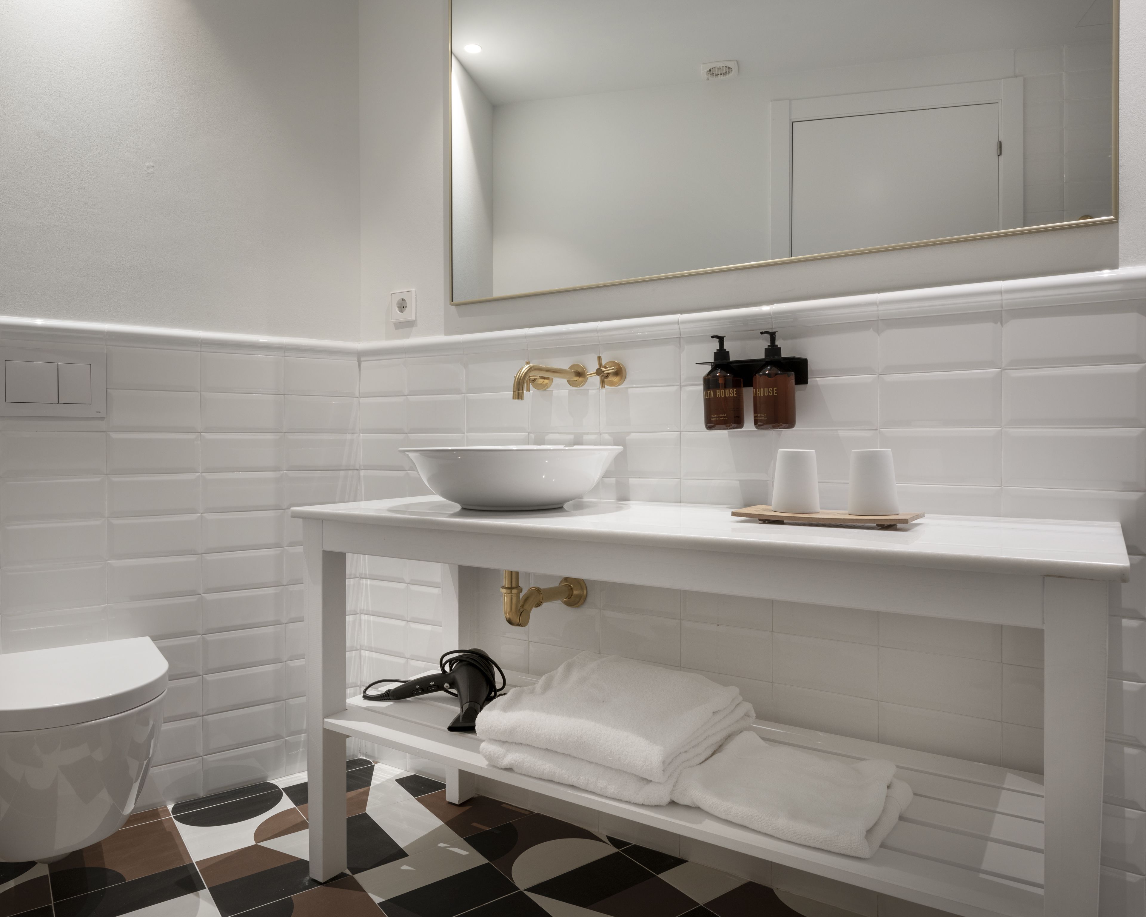 Een badkamer met een witte wastafel, een spiegel en een handdoekhouder.