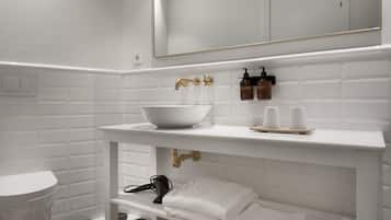Un bany amb un lavabo blanc, un mirall i un penjador de tovalloles.