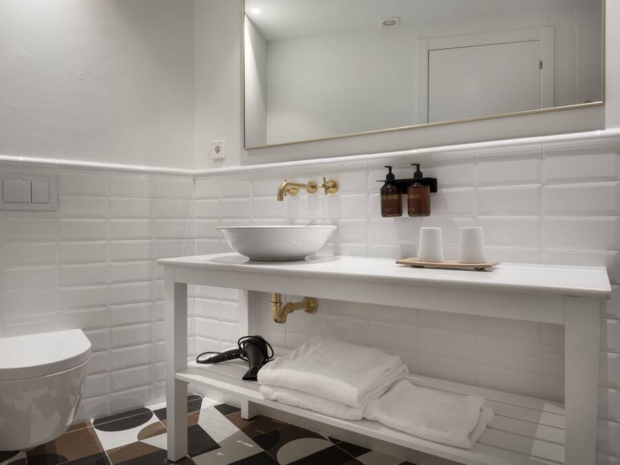 Un bany amb un lavabo blanc, un mirall i un penjador de tovalloles.