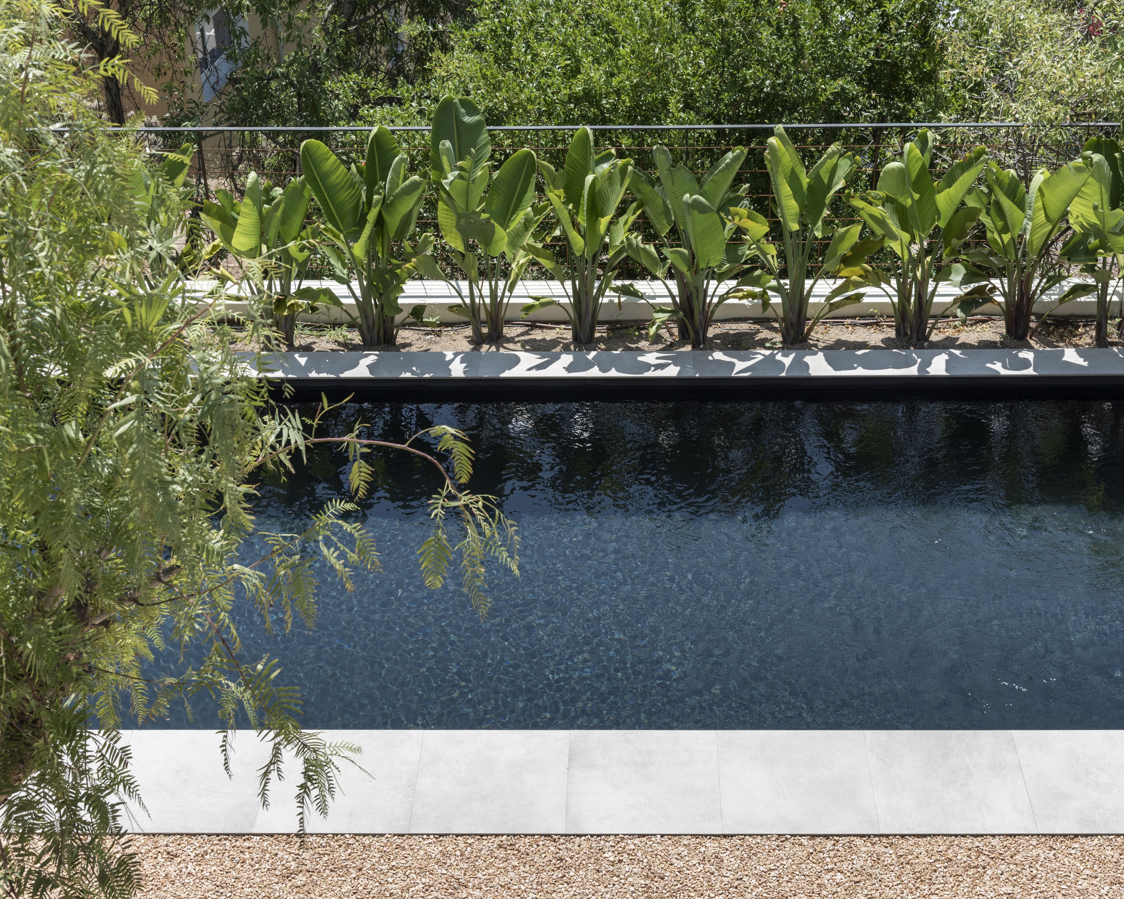 Una piscina rectangular amb superfície d'aigua nítida, envoltada per un sòcol de formigó i una zona de grava.