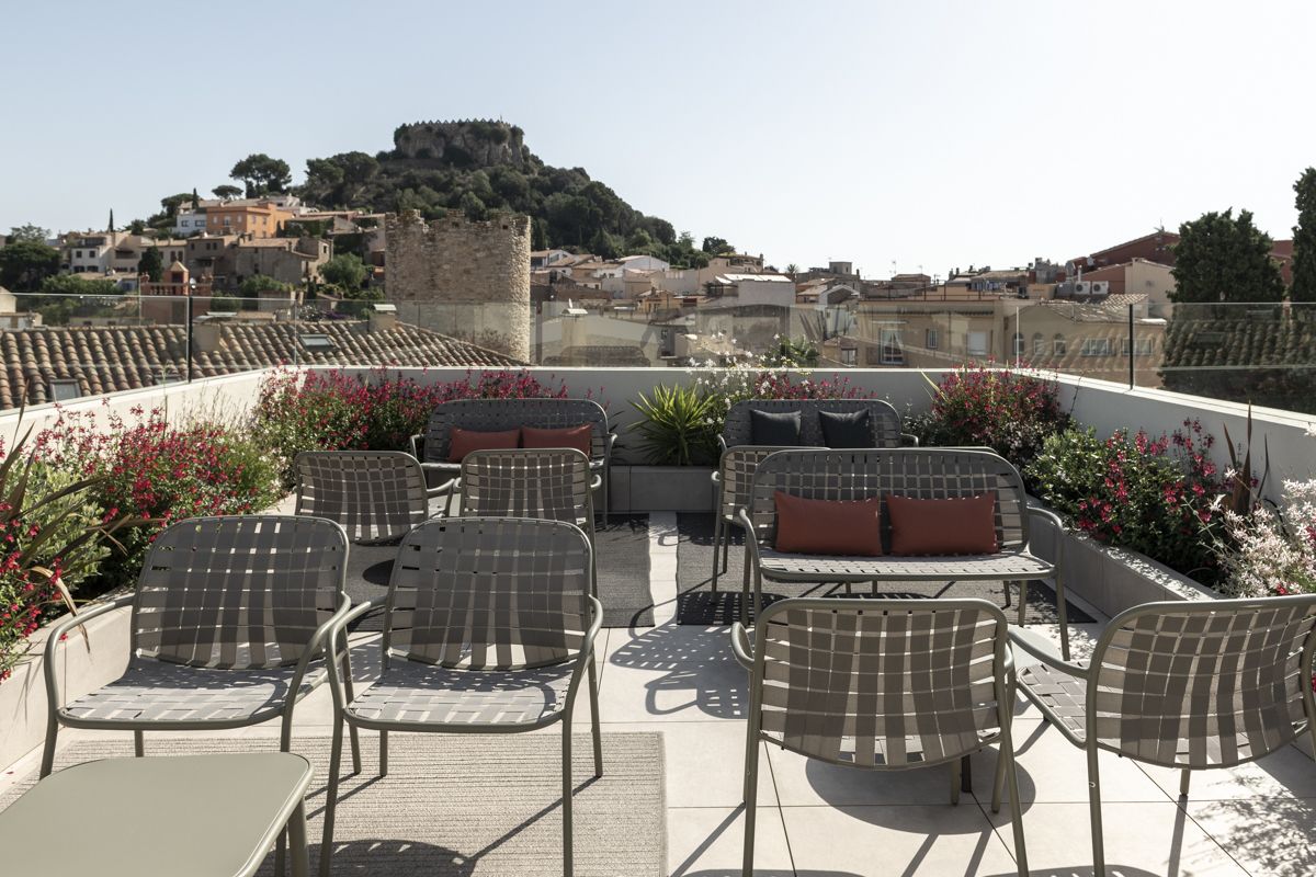 Una terraza en la azotea con mobiliario exterior, vistas a la ciudad y un castillo al fondo.