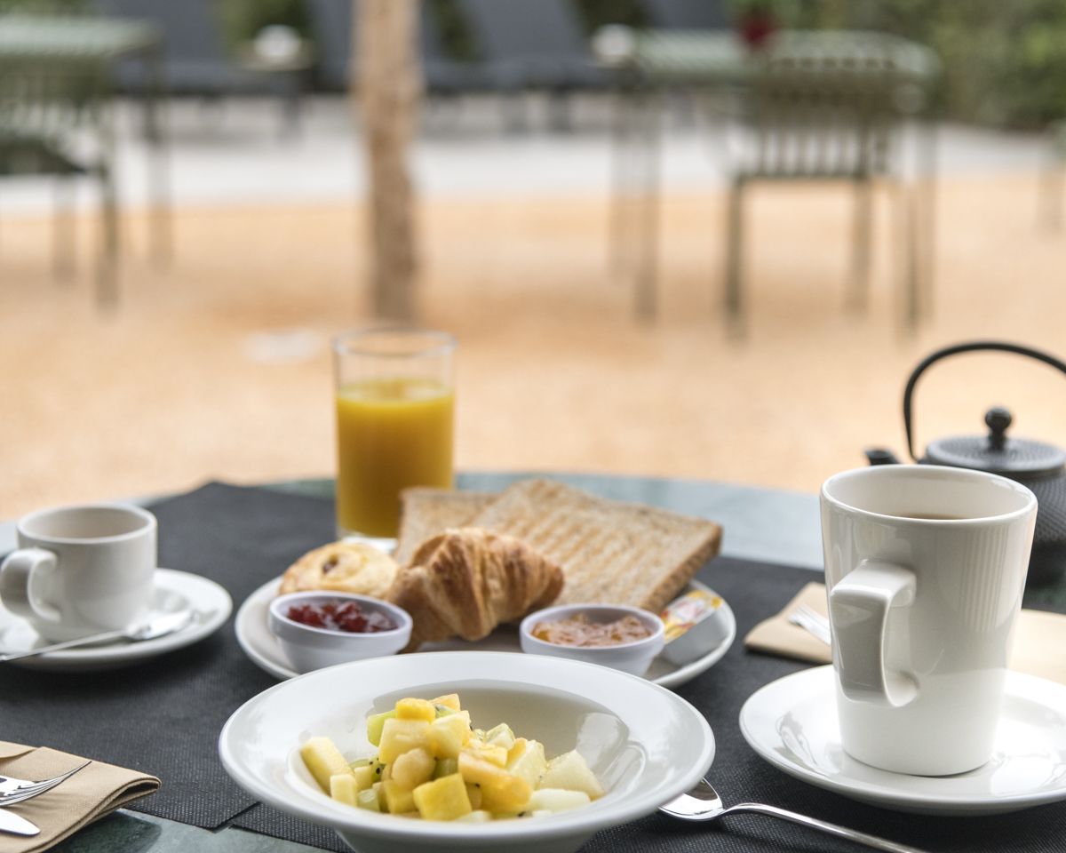 A breakfast setting with a table, plates, cups, and a teapot.