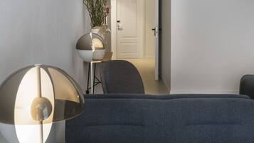 Una sala moderna con sofá, lámpara y planta en maceta.