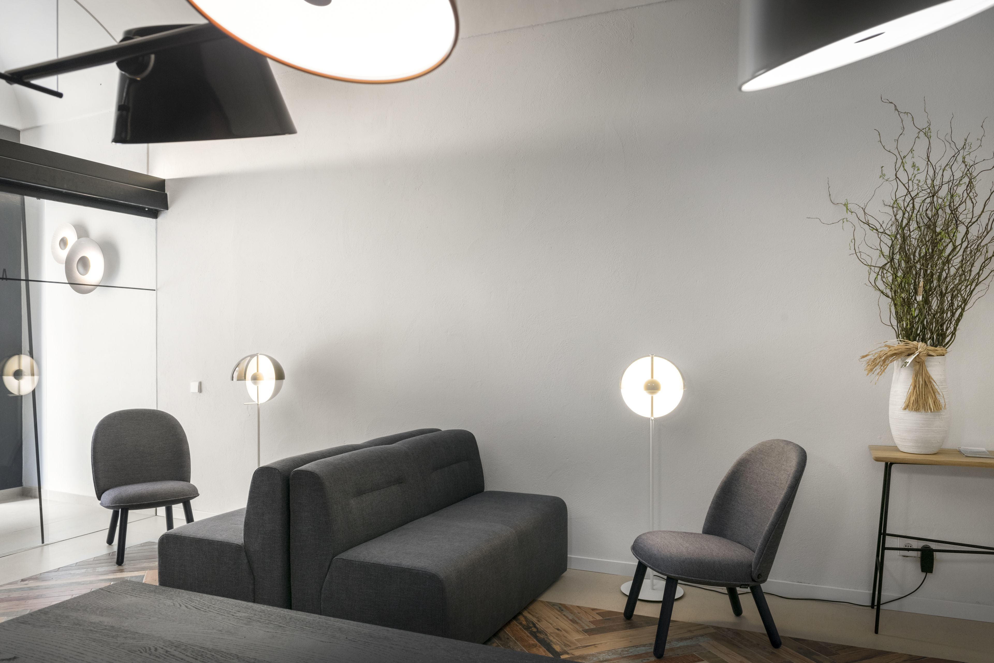 A modern living room with a grey sofa, two armchairs, and a floor lamp.