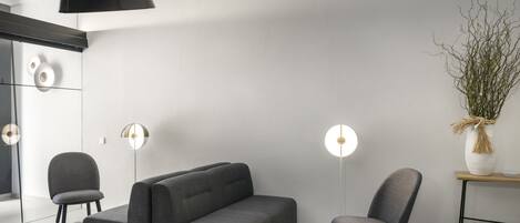 A modern living room with a grey sofa, two armchairs, and a floor lamp.