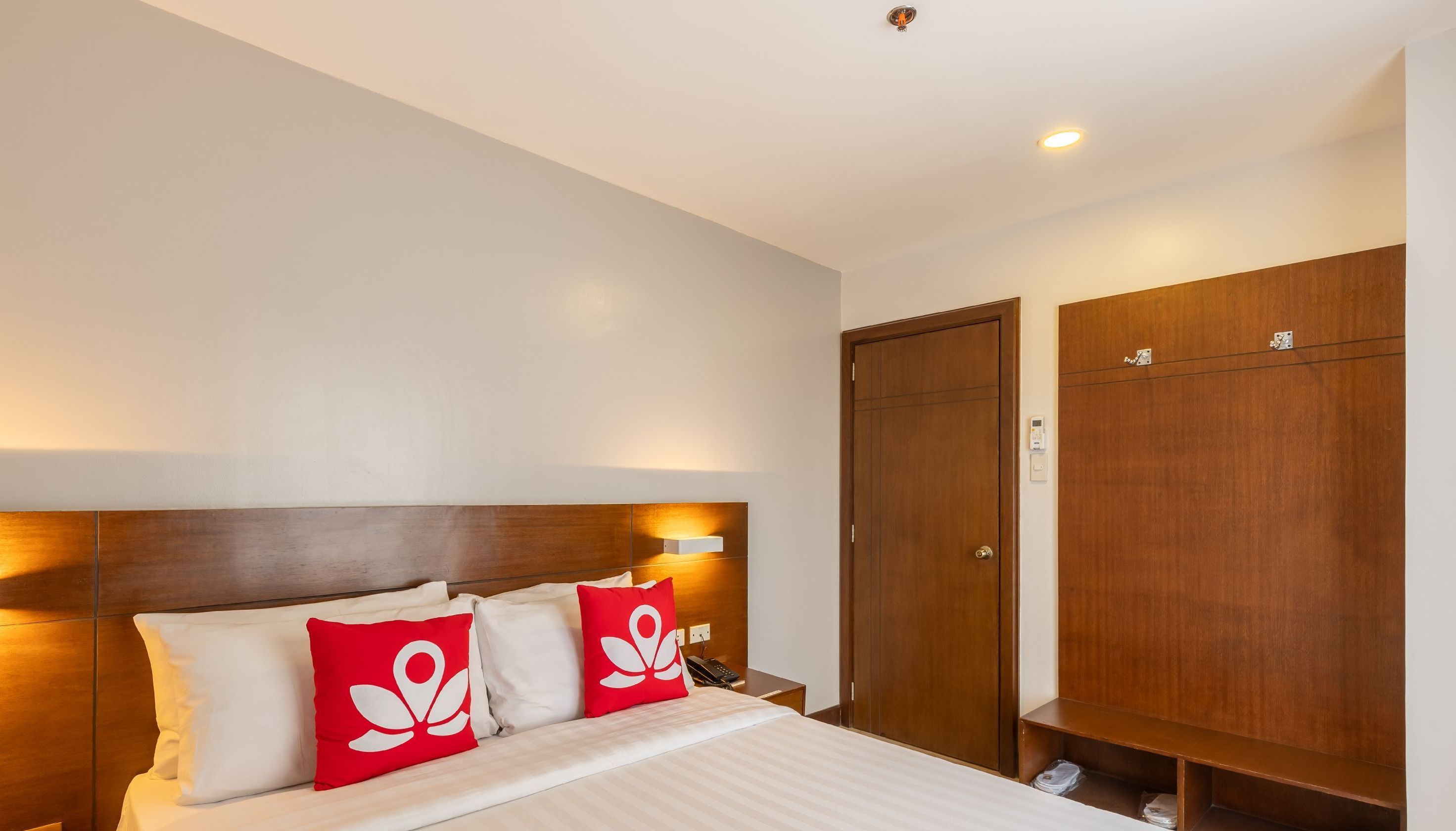 Une chambre d’hôtel avec un lit, une table de chevet et une armoire.