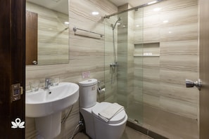 Un baño con cabina de ducha de vidrio, lavabo blanco y retrete.