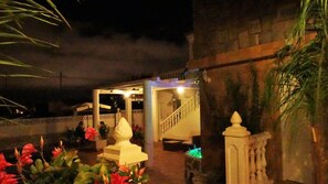 A covered outdoor area with a staircase leading to an upper level, surrounded by plants and flowers. - Hotel Casa Día y Noche (Calpe)